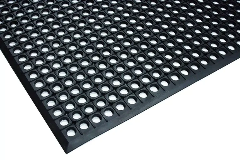 Detalhe de ângulo de um tapete profissional antiderrapante para cozinha industrial STARMIX KitchenMat fabricado em borracha nitrílica com furos e bordas chanfradas, sobre fundo branco.