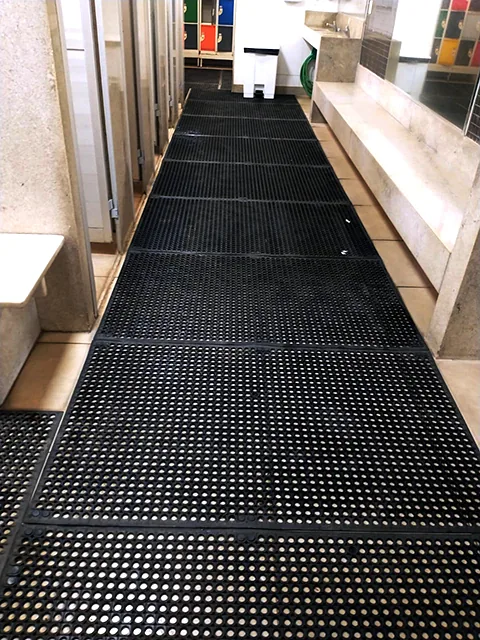 Estrado de borracha antiderrapante modular com conectores instalado em vestiário industrial